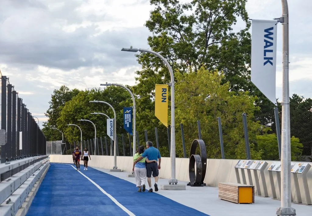 people walking along blue shared use path with typographic banners