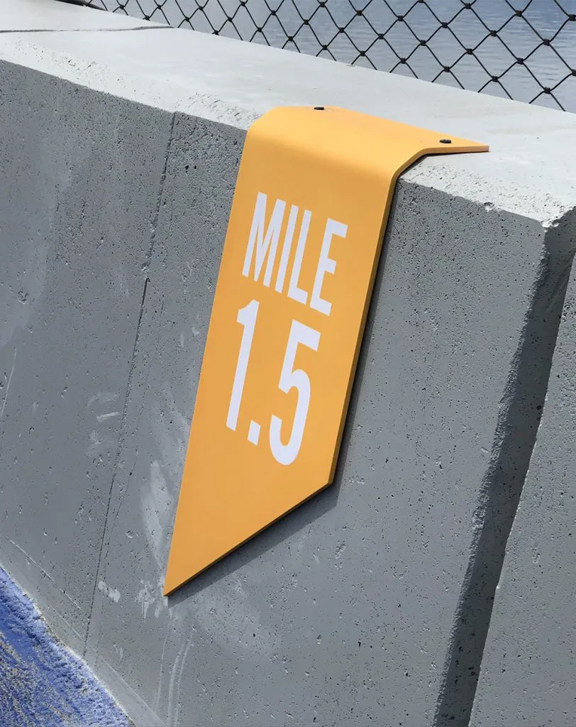 Modern yellow mile marker sign on concrete barrier