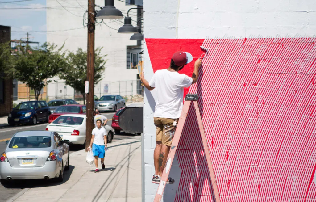 man on ladder painting a mural