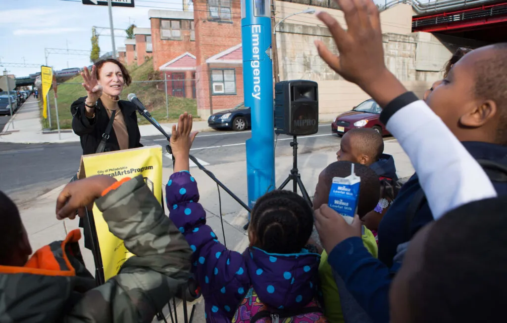 woman speaking to a crowd at city-wide art exhibition in Philadelphia