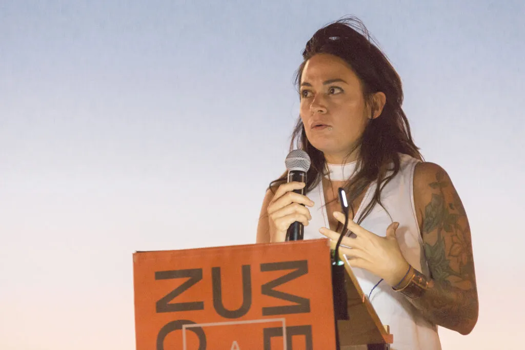 Woman speaking at orange and black branded podium