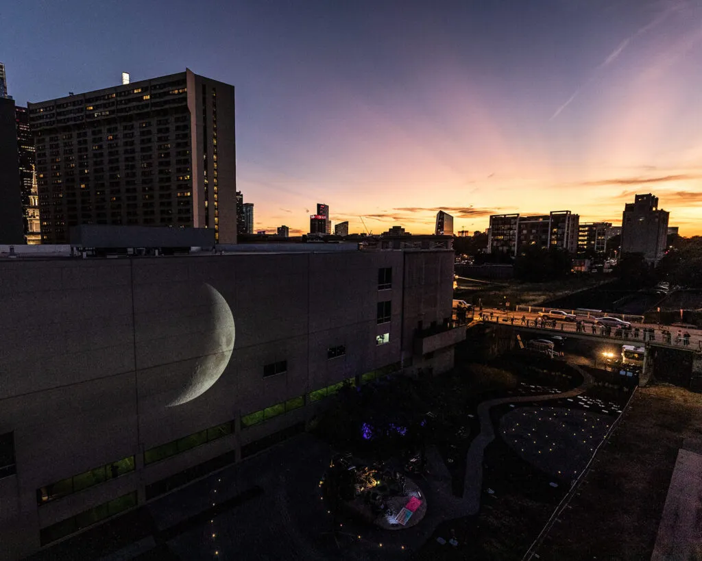 sunset over a large arts festival event with hundreds of people and projection mapping exhibition