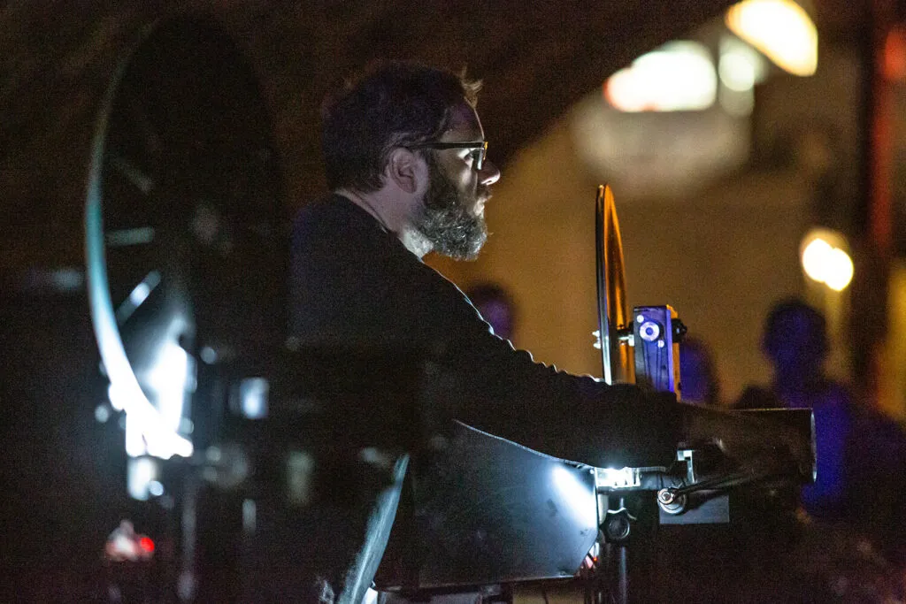 man operating reel to reel projection equipment at arts festival