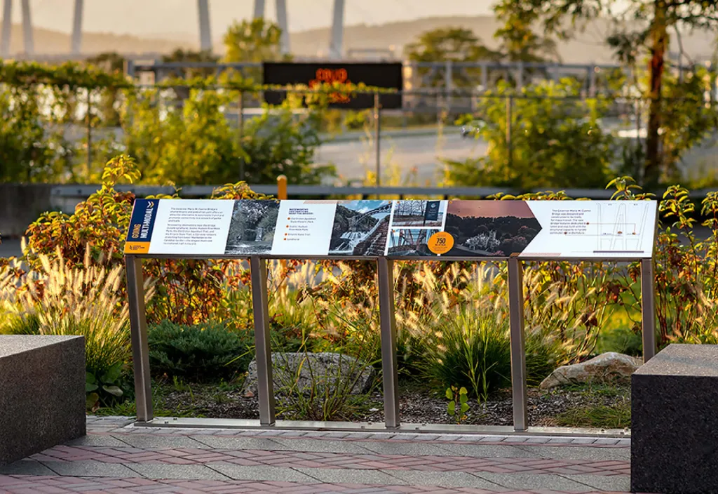 Interpretive panel with landscaping and large suspension bridge in background