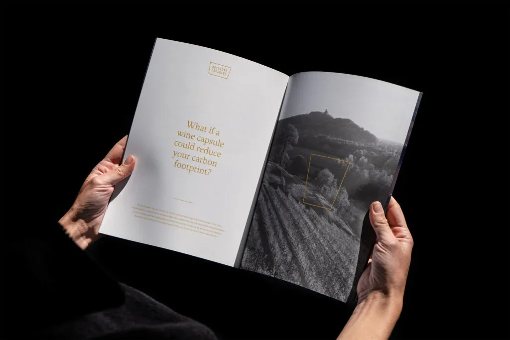 hands holding open a sales brochure for an American wine company featuring a large serif headline and photo of a vineyard