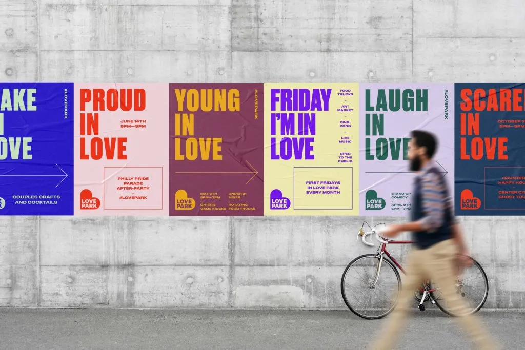 man walking in front of colorful branded wheat paste poster campaign for city park