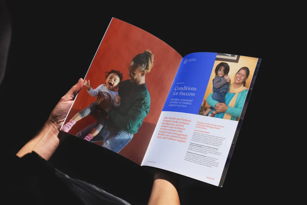 Hands holding a colorful mock up of an open brochure with big images and copy