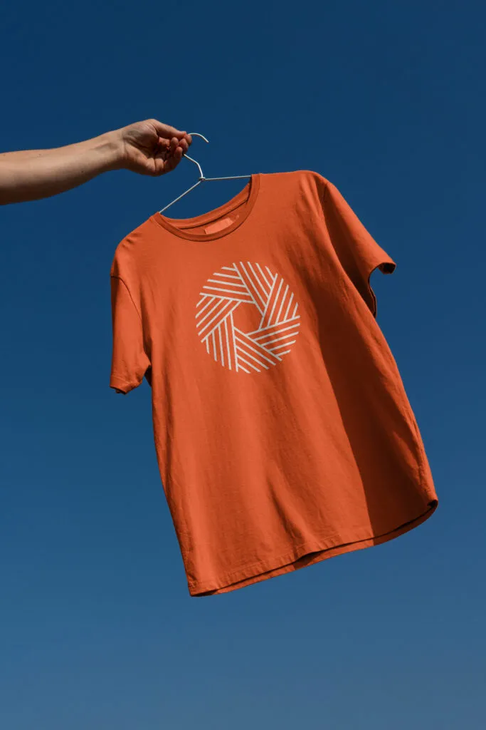 hand holding orange t-shirt mock-up with modern mono-weight radial logo design