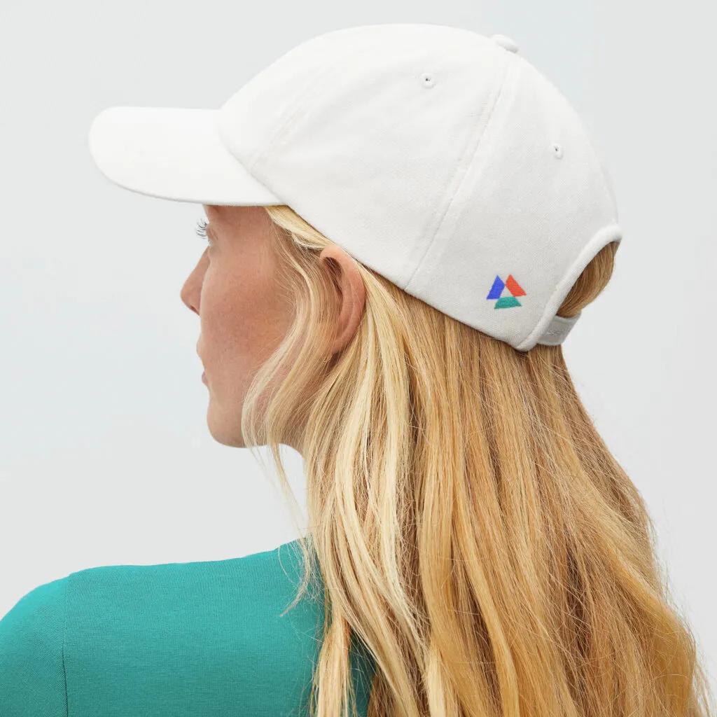 woman wearing a white baseball hat with small 3-color logo on back