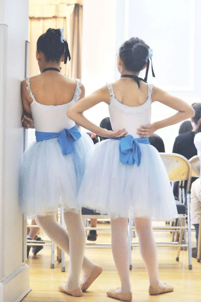 two young ballet students in the back of the classroom