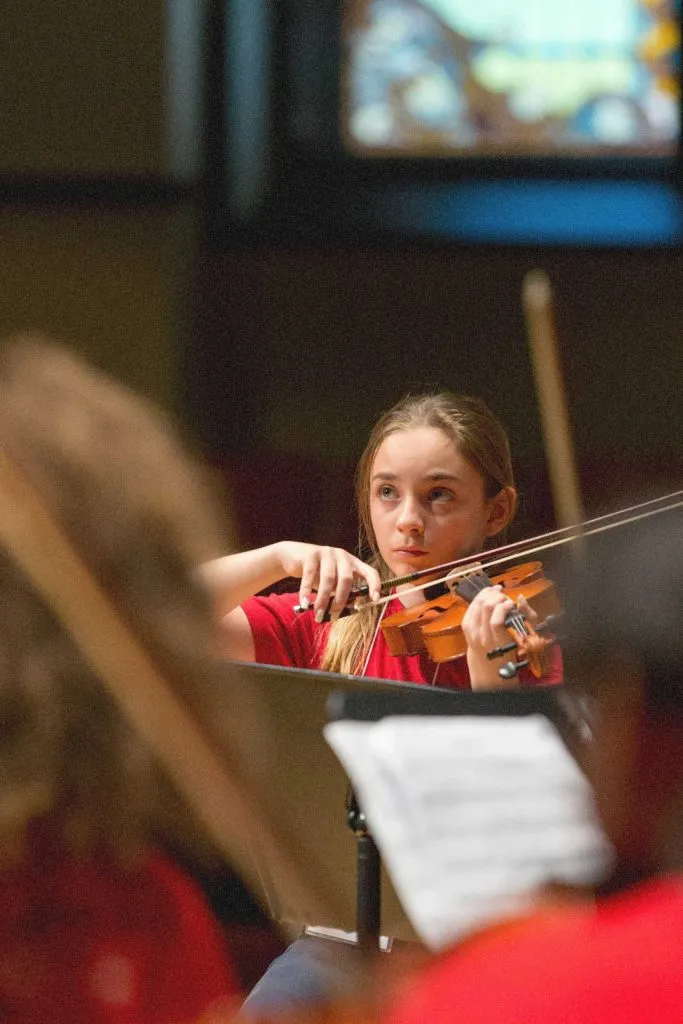 young girl playing the violin in classroom