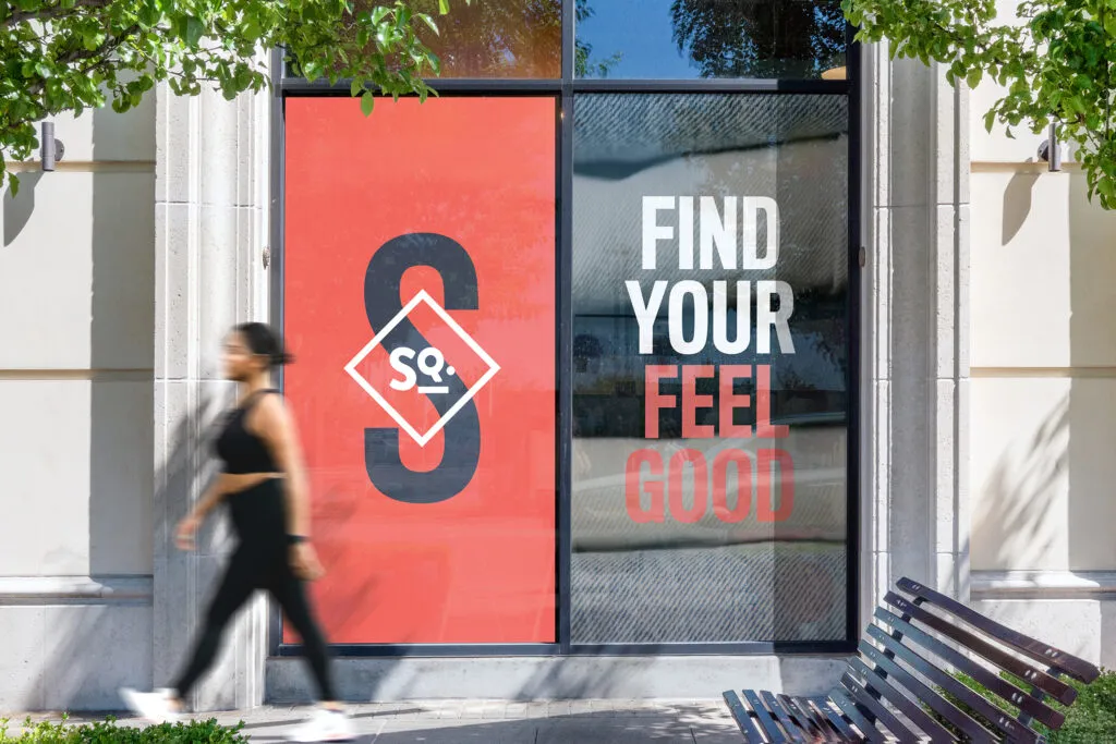 woman walking in front of bold window graphics with black and red logo and san serif messaging