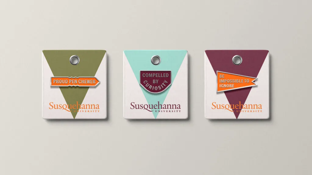 Three enamel pins with branded packaging, liberal arts college merch designed for Susquehanna University by J2