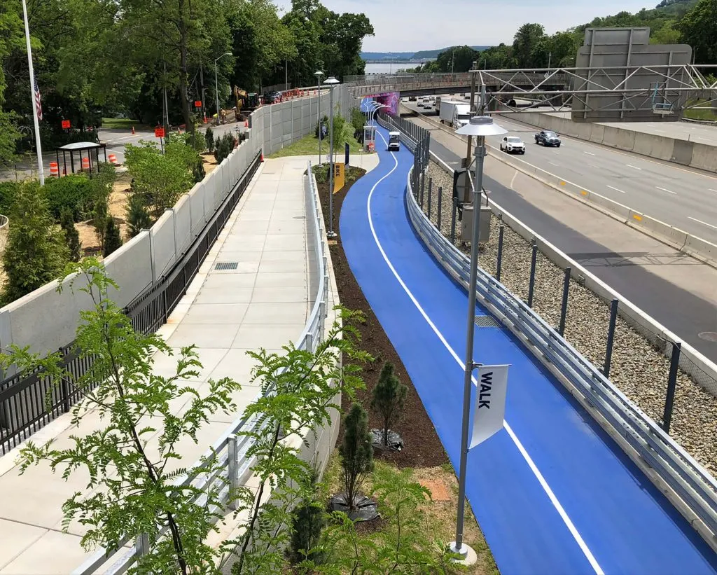 blue shared use path along highway with minimal landscaping