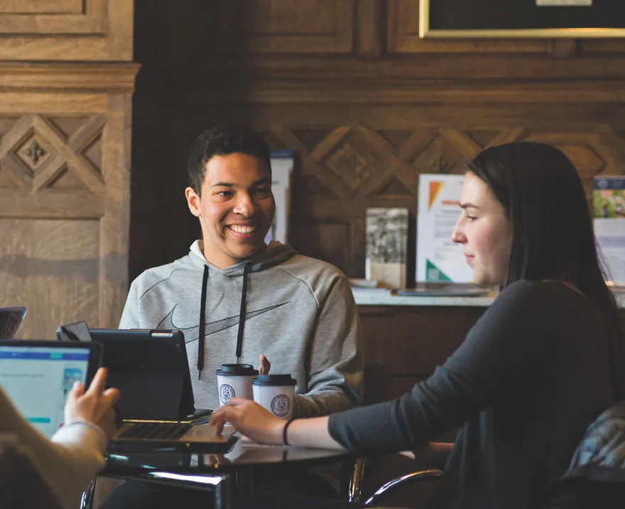 high school students work together on laptop computers in a coffee shop