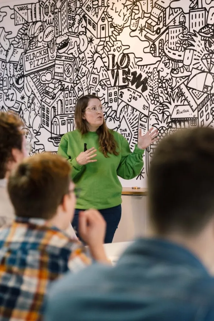 Manager leading a staff meeting in an office with a mural in background