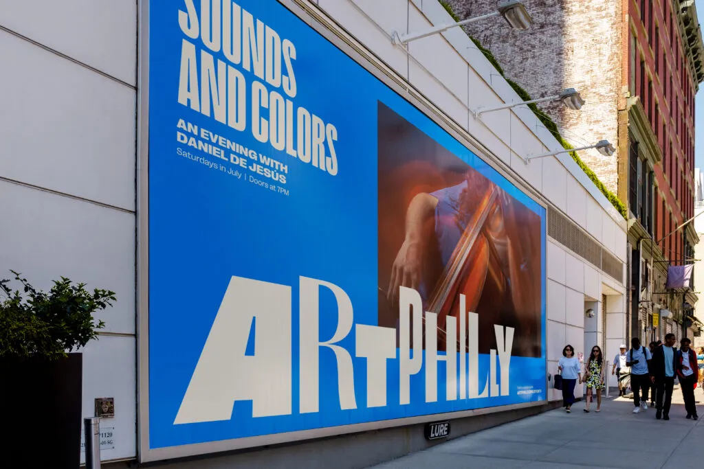 Lighted billboard attached to stone building. Graphic design by J2 for ArtPhilly.