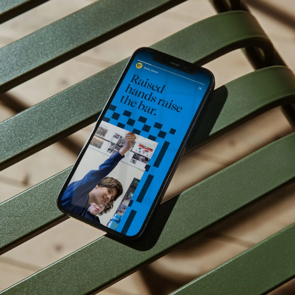 Smart phone displaying branded instagram story as part of Breck School branding project by J2. The phone is on a green bench.