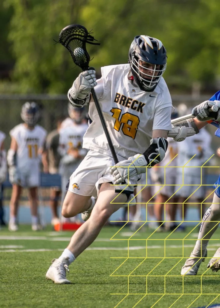 Private school student wearing sports jersey and playing competitive lacrosse on a recreational field.