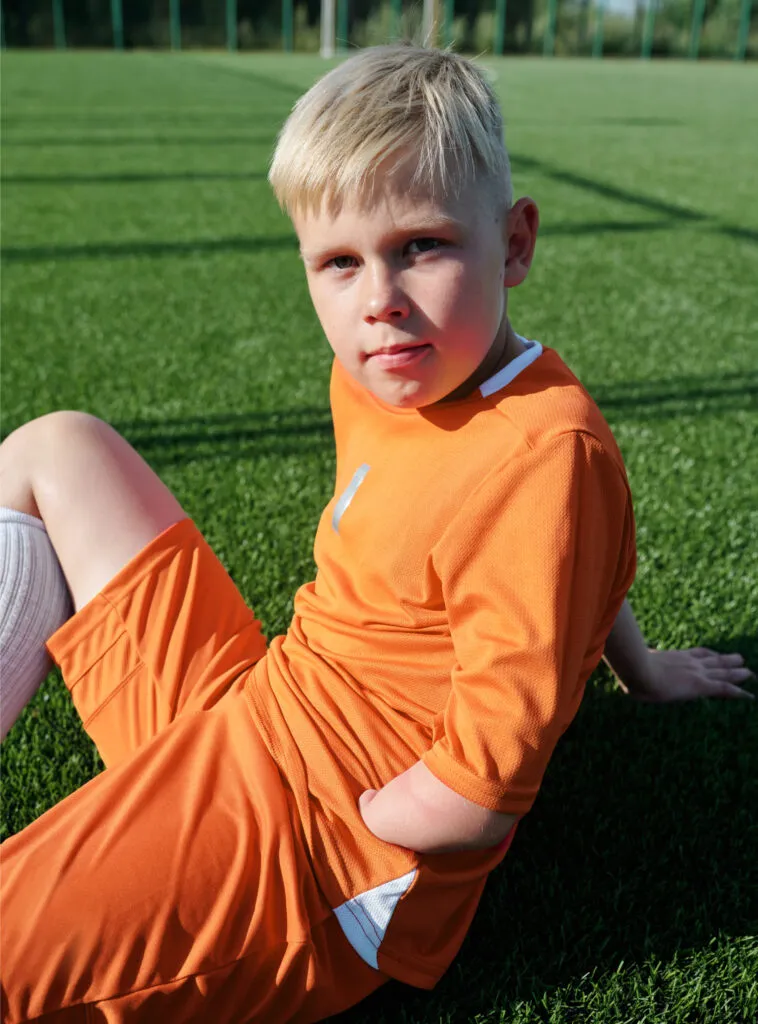 Smiling, differently-abled young soccer player taking a rest on the turf at PlayaRaya