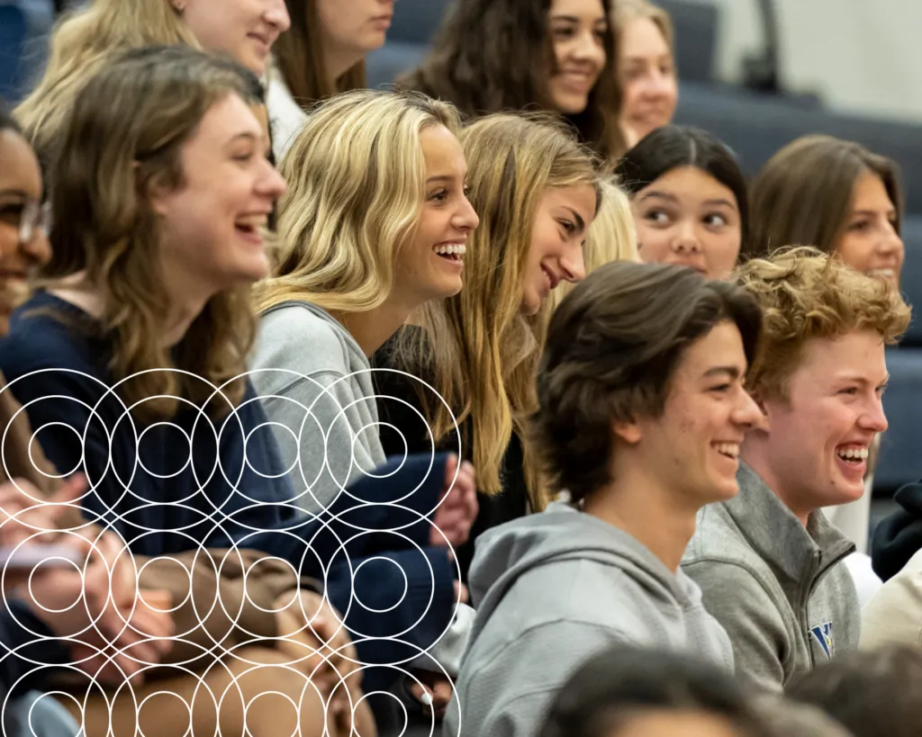 Laughing students sitting together in high school gym.