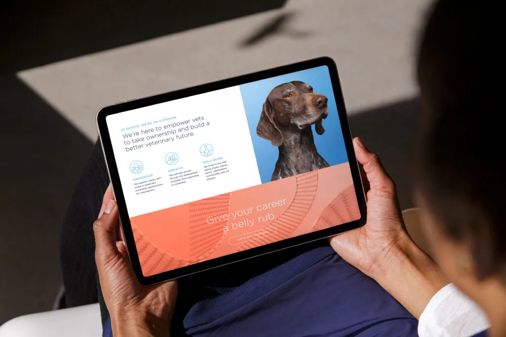 person holding an iPad screen displaying infographics and dog photo, branding and graphic design by J2 for Suveto vet services