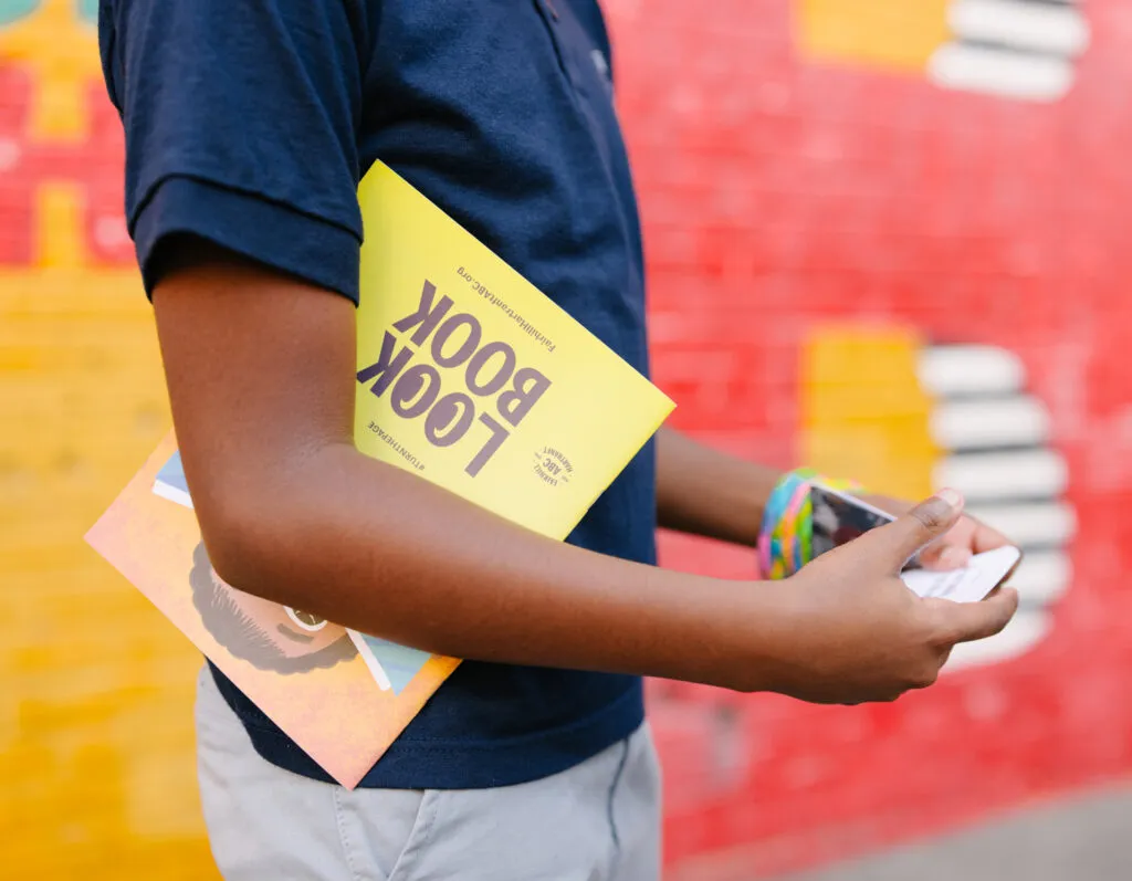 Teen boy reading brand look book and playing with cards. Literacy Rich Initiative brand by J2.