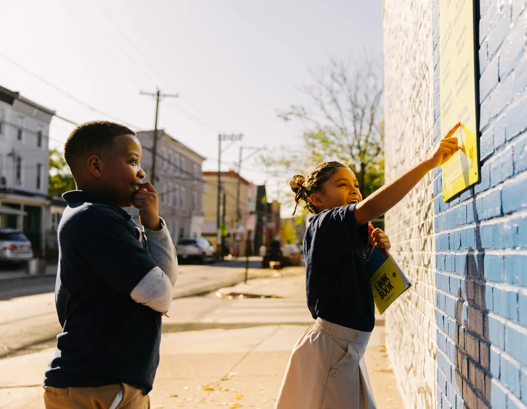 Boy and girl interacting with and pointing at mural. Literacy Rich Initiative brand by J2.