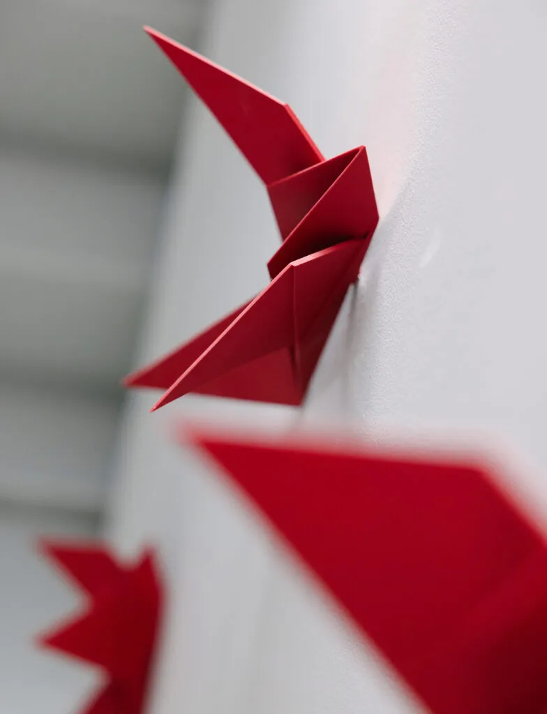 Detail shot of final origami bird, with unfolded paper in the background